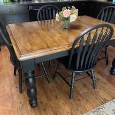 a kitchen table with four chairs and a vase of flowers on the counter top in front of it