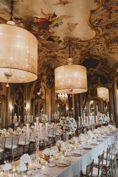 an elaborately decorated dining room with chandeliers and white flowers on the tables