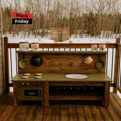 an outdoor kitchen made out of pallet wood on a deck with snow and trees in the background