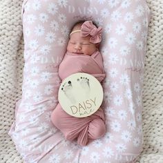 a baby wrapped in a pink blanket is laying on a pillow with the words daisy written on it