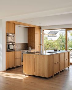 a large kitchen with wooden cabinets and an island in the middle of it, along with sliding glass doors leading outside