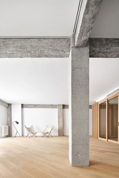 an empty room with white chairs and wooden floors