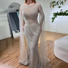 a woman in a white dress standing on a wooden floor with a veil over her head