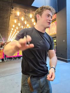 a man standing in front of a building holding his hand out