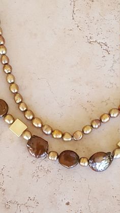 "Swarovski Pearl and Shell Necklace.  This beauty has 2 strands.  A mixture of chain and beading. The inner strand is chain with all swarovski pearls in a golden tone and measures to 20\".  The outer layer is a combination of chain and swarovski pearl, shell and gold plated metal beads and measures to 24\".  From elegance to casual, wear this with any outfit. Materials; Swarovski Pearls Shell Beads Gold Plated Metal Square Beads Gold Plated Toggle Clasp Gold Plated Chain Always a winner with pea Golden Pearl, Square Beads, Square Bead, Wire Wrapped Rings, Shell Necklace, Pearl Shell, Swarovski Pearls, Leaf Pendant, Wrap Rings