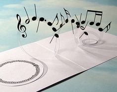 an image of musical notes coming out of a piece of paper that has been cut into