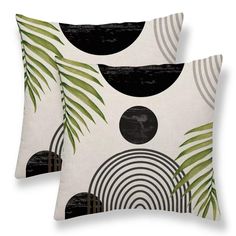 two black and white pillows with palm leaves on the front one has a circular design