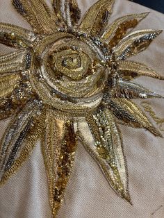 a gold and silver decorative piece on a white cloth with sequins in the center