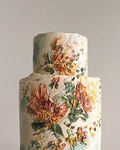 a three tiered cake with flowers painted on it