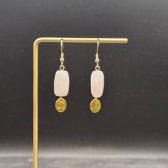 These boho dangle earrings feature 14mm x 10mm rose quartz nuggets with small 8mm x 10mm gold-plated oval charms dangling from the bottom.  Rose Quartz is known as the stone of universal love, and is said to restore trust and harmony in relationships and encourage unconditional love. Rose Quartz purifies and opens the heart at all levels to promote love, self-love, friendship, deep inner healing, and feelings of peace.  These lightweight earrings measure approximately 1 7/8 inches from the top of the ear wires to the bottom of the brass charm. The ear wires are made of gold-plated surgical steel, making these earrings safe for sensitive ears. They weigh approximately 0.1 ounce each! Shipping: Domestic shipping is always free here at MayaMadeThis! When will my item ship?  Every single item Pink Rose Quartz Earrings With Natural Stones, Elegant Nickel-free Rose Quartz Earrings, Nickel-free Rose Quartz Dangle Earrings, Handmade Rose Quartz Dangle Earrings, Rose Gold Dangle Earrings With Rose Quartz, Rose Quartz Ear Wire Earrings For Gift, Rose Quartz Earrings With Ear Wire As Gift, Rose Quartz Drop Earrings For Jewelry Making, Gold Rose Quartz Earrings For Gift