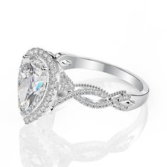 a pear shaped diamond engagement ring with an intricate band around the shans, set in 18k white gold