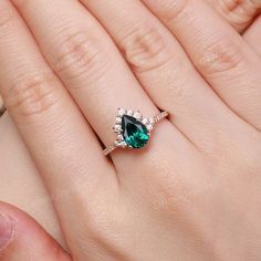 a woman's hand with a ring on it and a green stone in the middle