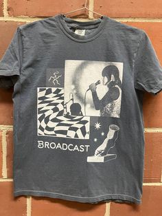 a t - shirt hanging on a brick wall with an image of a woman holding a microphone