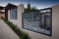 a modern house with an intricate metal screen on the front door and side yard area