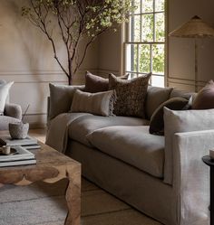 a living room filled with furniture and a tree in the middle of the room next to a window