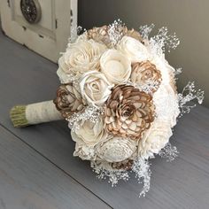 a bridal bouquet with white and brown flowers on a wooden table next to a door