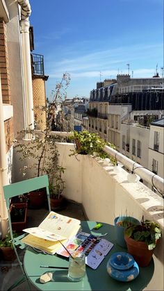 a table and chairs on a balcony with a view of buildings in the distance,