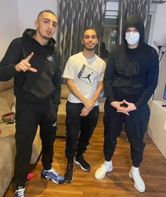 three men wearing face masks in a living room