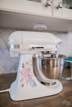 a white mixer sitting on top of a kitchen counter next to a blue and white bowl