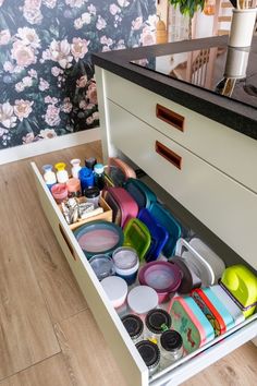 an open drawer in a kitchen filled with lots of clutter and paint bottles on the floor