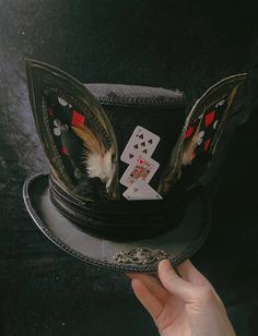 a person holding up a hat with playing cards on it