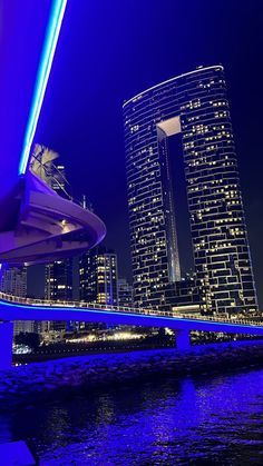 the city is lit up at night with bright blue lights and skyscrapers in the background