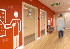 a man walking down a hallway with red walls and white lettering on the wall behind him