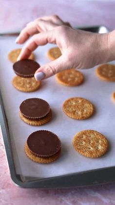 there is a tray with cookies on it and a hand reaching for one cookie in the middle