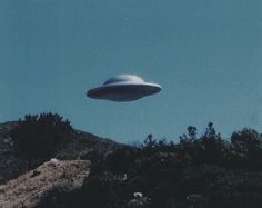 an alien flying in the sky over a hill