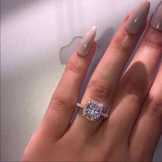 a woman's hand with an engagement ring on top of her finger, next to an apple