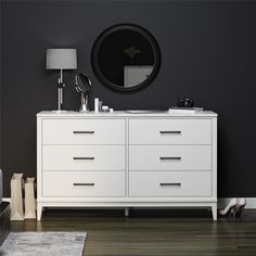 there is a white dresser with two mirrors on it and a lamp next to it