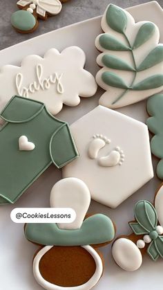 decorated cookies in the shape of baby's clothes and other items on a plate