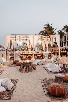 an outdoor wedding setup on the beach with white draping and hanging chandeliers