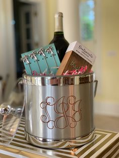 a wine bottle and some chocolates in a silver pot on a table with striped napkins