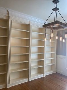 a chandelier hanging from the ceiling in a room with empty bookshelves