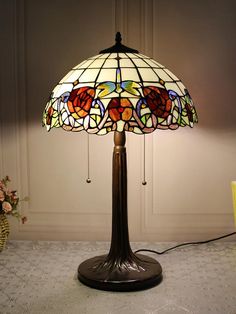 a stained glass lamp on a table next to a vase