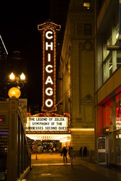 the chicago theatre marquee is lit up at night with people walking down the sidewalk