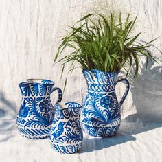 three blue and white vases with plants in them