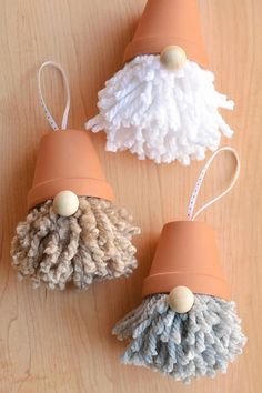 three pom - poms are sitting on a wooden table, one is orange and the other is white