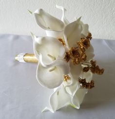 a white flower bouquet with gold accents on a table