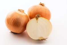 three onions sitting next to each other on a white surface