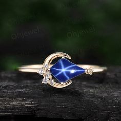 a gold ring with blue and white stones on it, sitting on top of a piece of wood