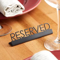 the word reserved is placed next to a wine glass and plate on a wooden table