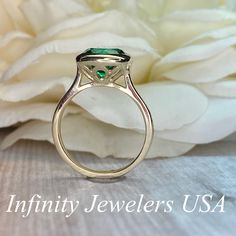 "The ring pictured is lab created emerald #5950 -Approximate total carat weight: 2.70ctw diamond equivalent -Center Stone Size: 9mm - approx. 2.70ct diamond equivalent -Center Stone Shape: round (set with cushion shape bezel) -Gem Type: lab created emerald -Stone Clarity: VS2 -Stone Color: lively green -Moh's Scale: 8.5 hardness -Metal Type and Purity: 14k yellow gold -Setting: bezel set -Stock Ring Size: 5.75 -Country of Manufacturing: USA (Michigan) For customization please contact us. If you Round Emerald Ring For Anniversary, Emerald Cluster Ring For Anniversary, Formal Solitaire Sapphire Ring For May Birthstone, Emerald Ring With Round Shape, Emerald Cut Ruby Ring With Prong Setting For Anniversary, Green Diamond Ring With Center Stone, Anniversary Emerald Cluster Ring, Green Jewelry With Halo Setting For Promise, Emerald Ring With Accent Stones For May Birthstone