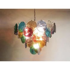 a chandelier hanging from the ceiling with many different colored glass discs on it