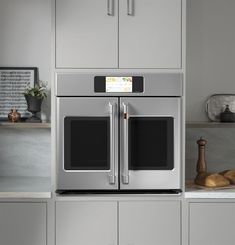 a kitchen with stainless steel appliances and white counter tops, gray cabinets, and wooden cutting board