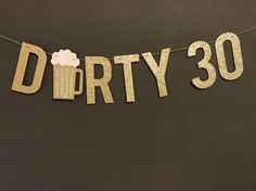 a banner that says dirty 30 hanging from a string on a black wall with gold glitter letters