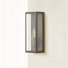 a wall light mounted on the side of a building with a clear glass paneled door