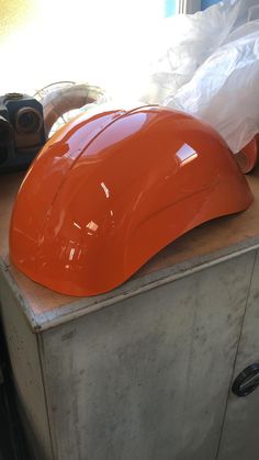 an orange hard hat sitting on top of a metal cabinet