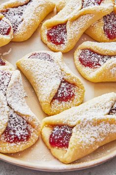 several pastries are arranged on a plate with powdered sugar and jelly toppings